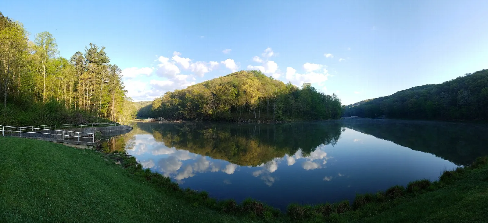 Wide view of Pine Lake reflecting wooded hills under a blue sky