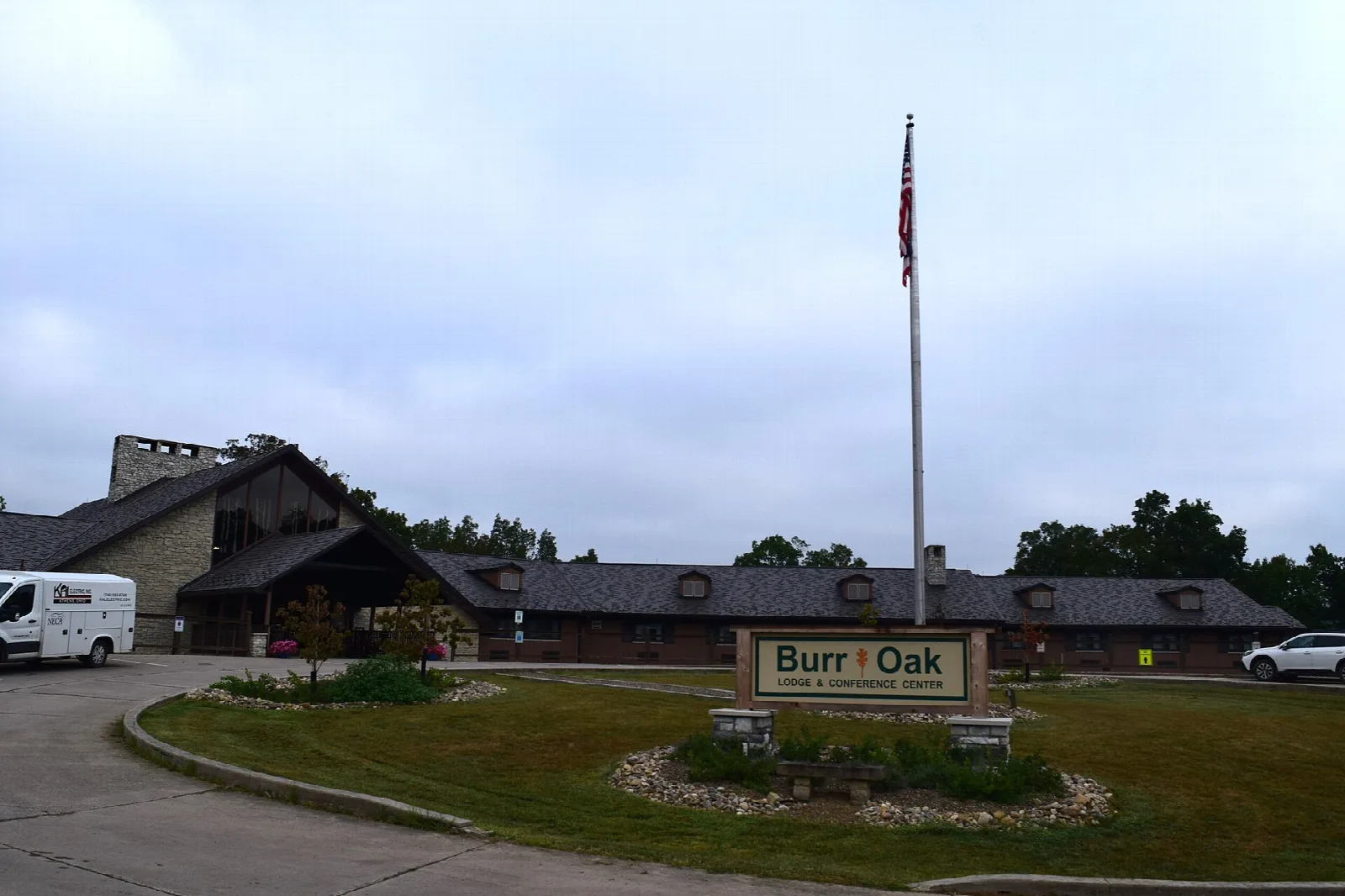 Low stone-and-timber lodge building with a flagpole and a Burr Oak sign out front