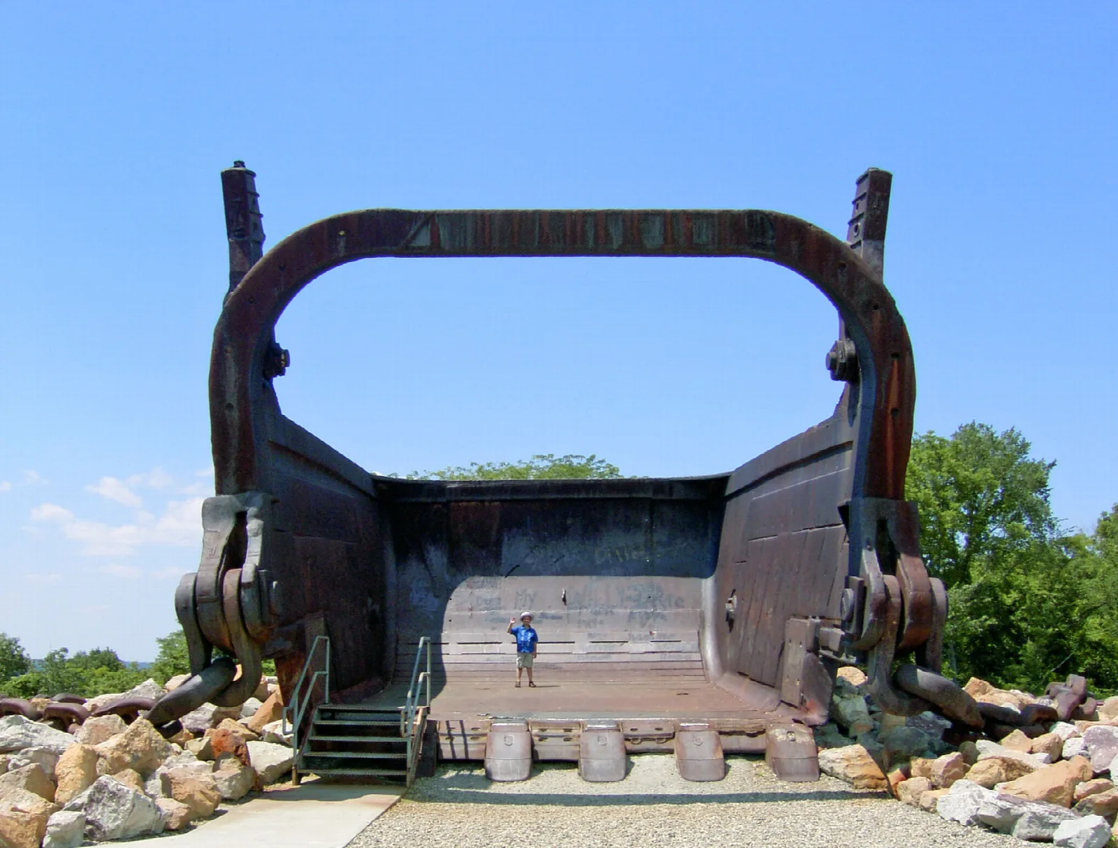 Giant dragline bucket seen head-on with a small person standing in front