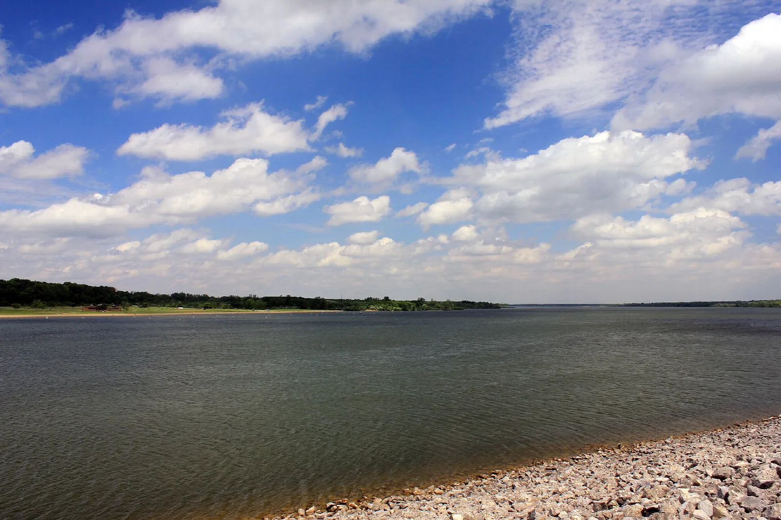 Broad lake with a pebble shore and a low tree line