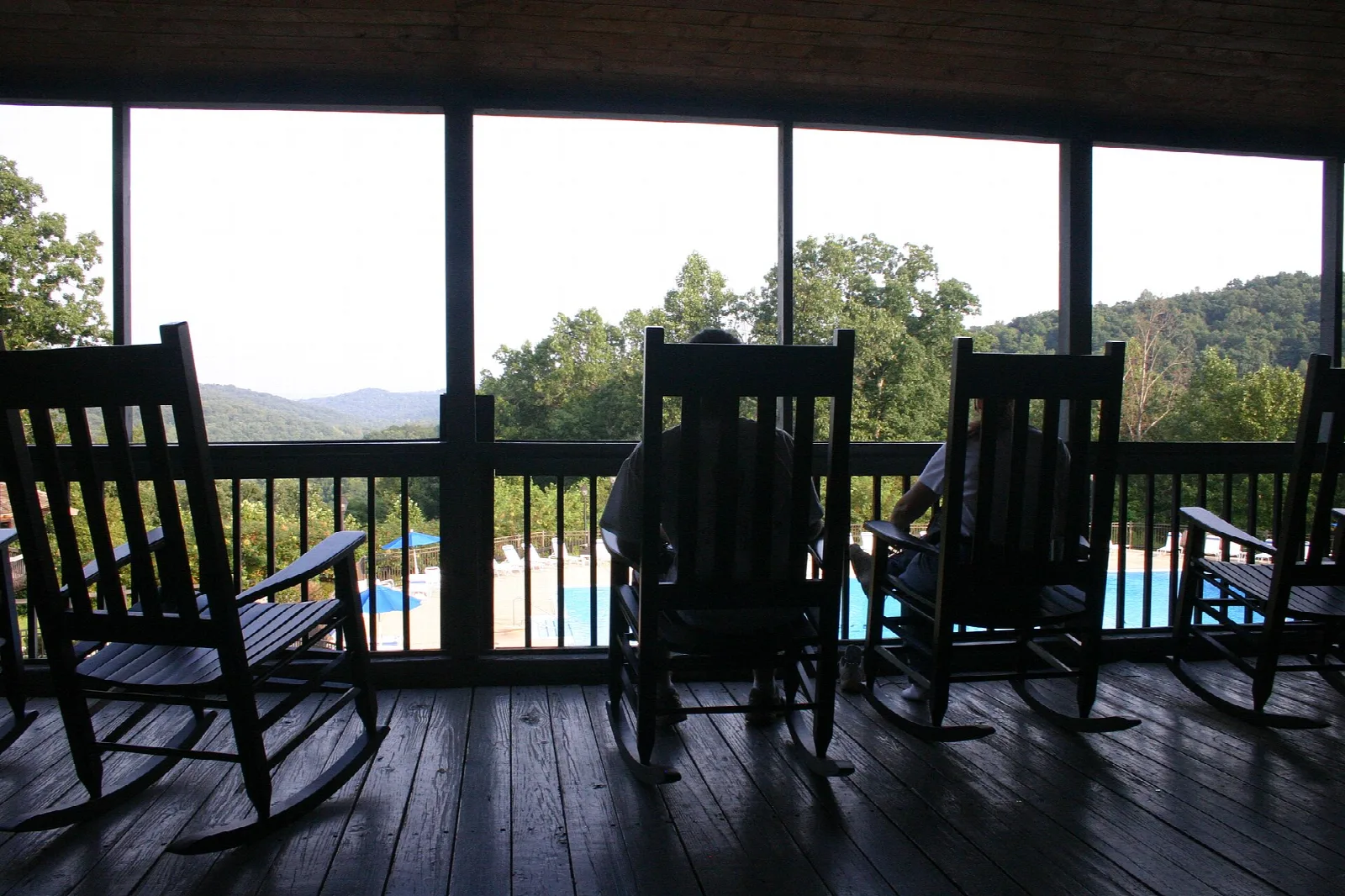 Rocking chairs on a lodge back porch looking out to trees and hills