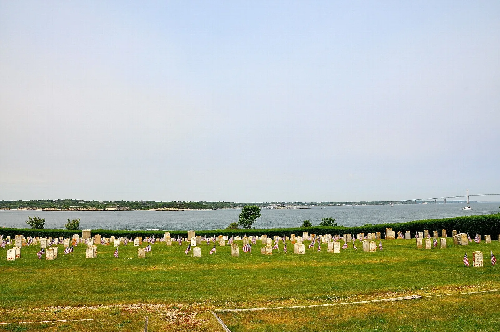 Rows of headstones in a grassy field beside the water