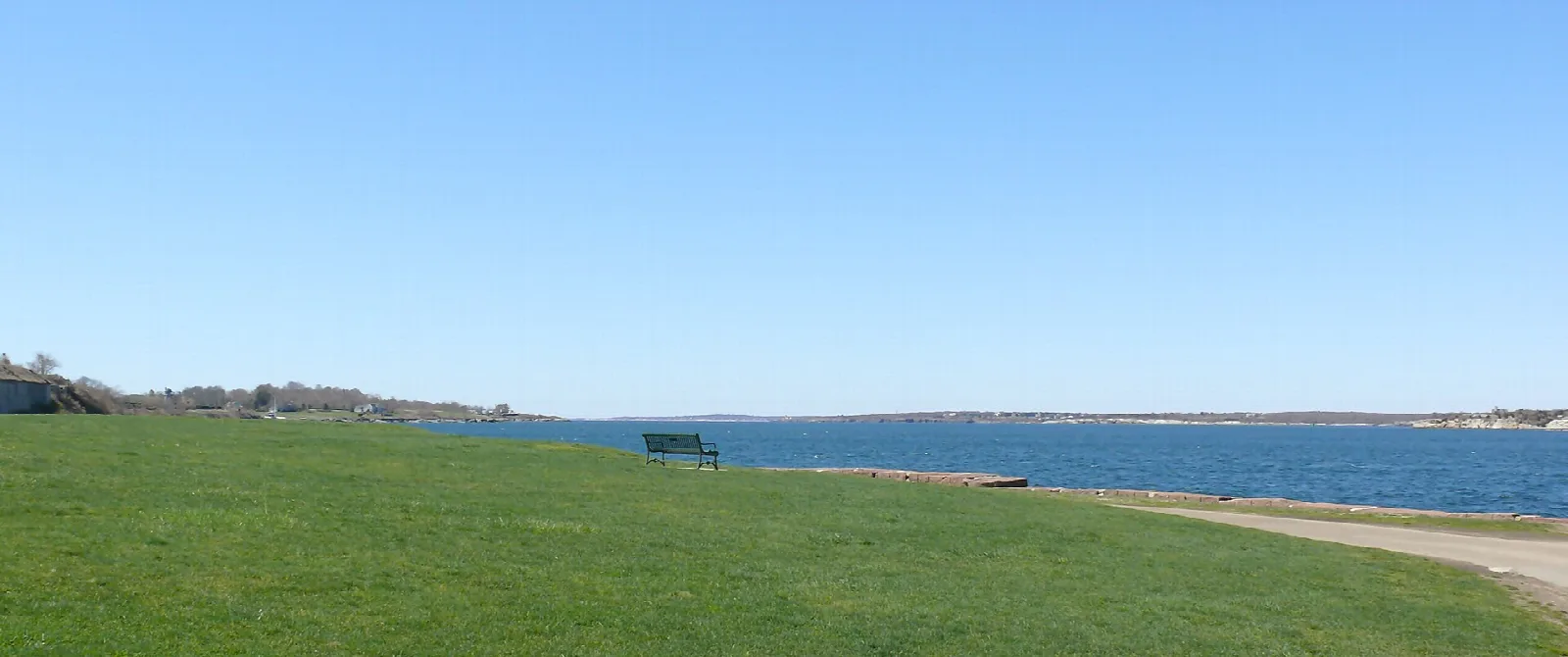 Green lawn sloping to a bay with a bench at the water's edge