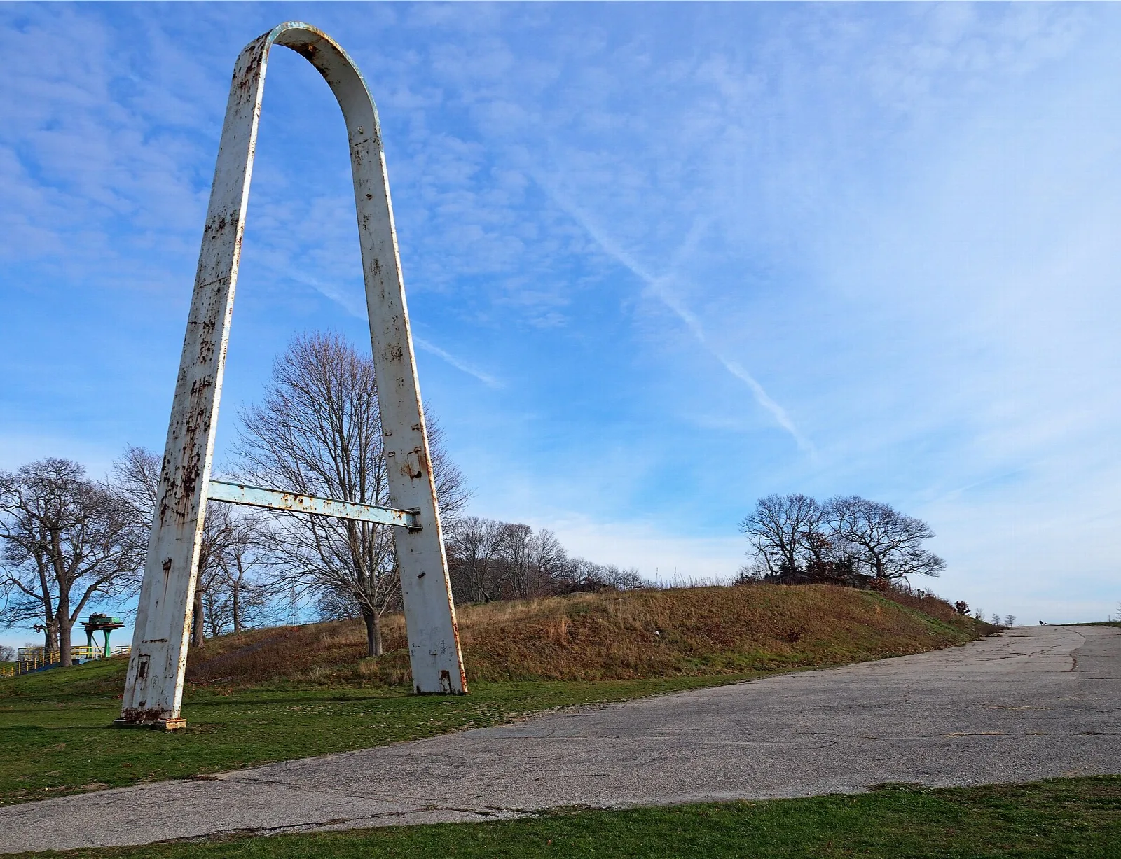 Tall white arch beside a paved path on a grassy rise