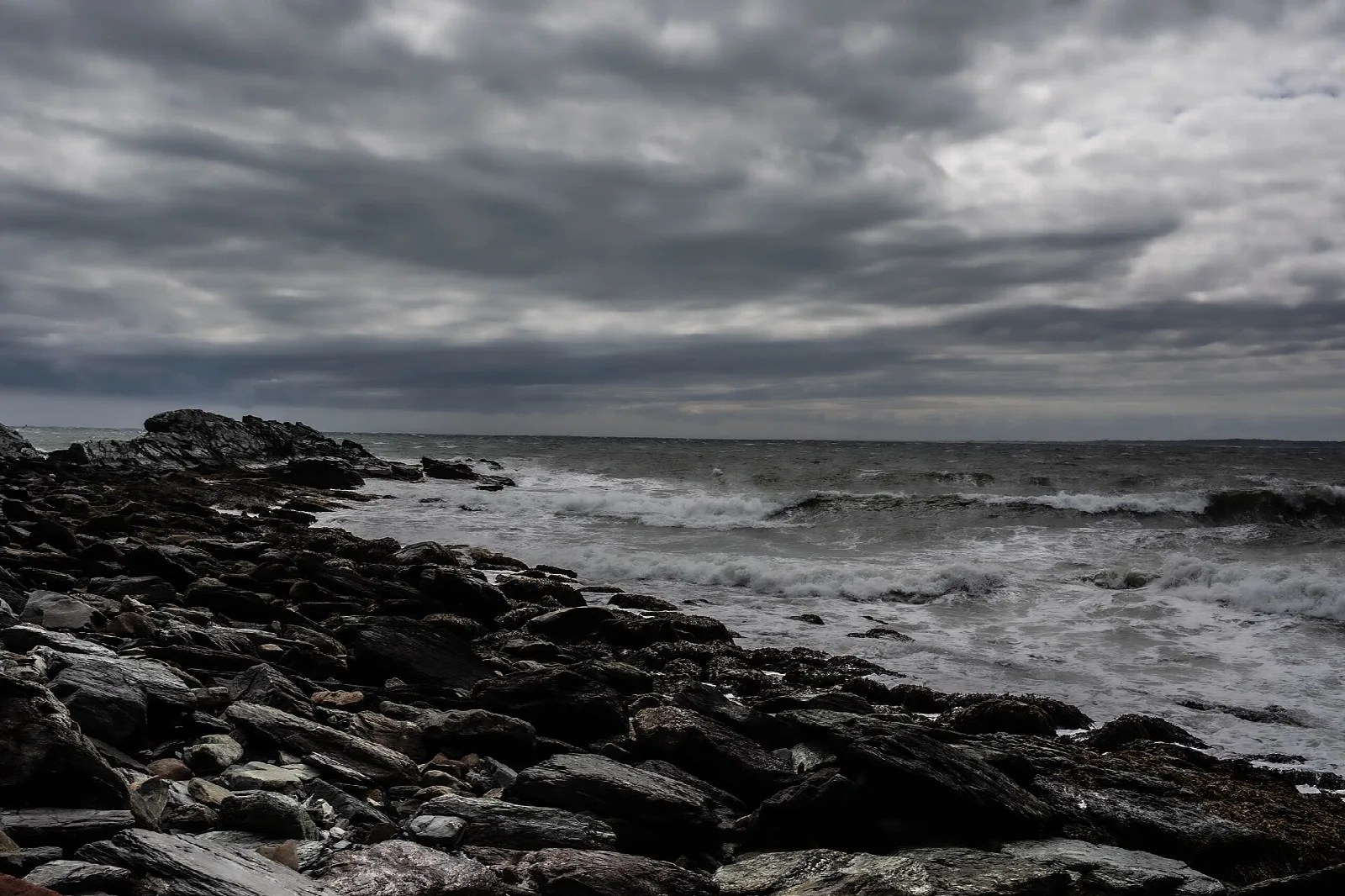 Dark rocky shoreline under heavy gray clouds