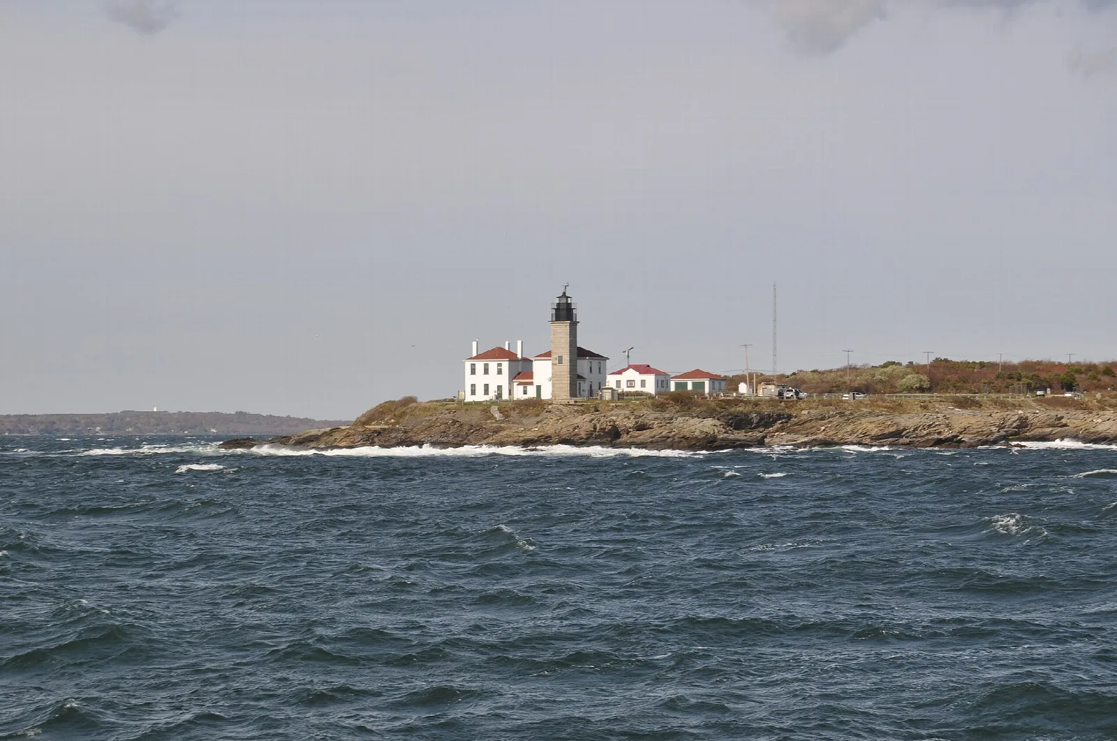 Lighthouse on a low rocky point seen across open water