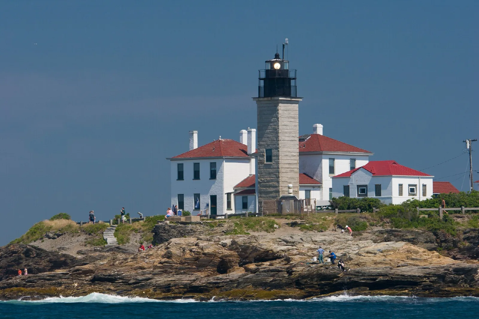 Lighthouse with white keeper's houses on a rocky point above the water