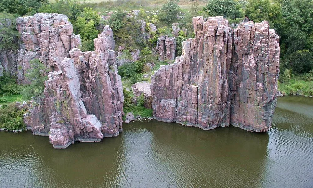 Two tall pink quartzite rock formations rising from a calm creek