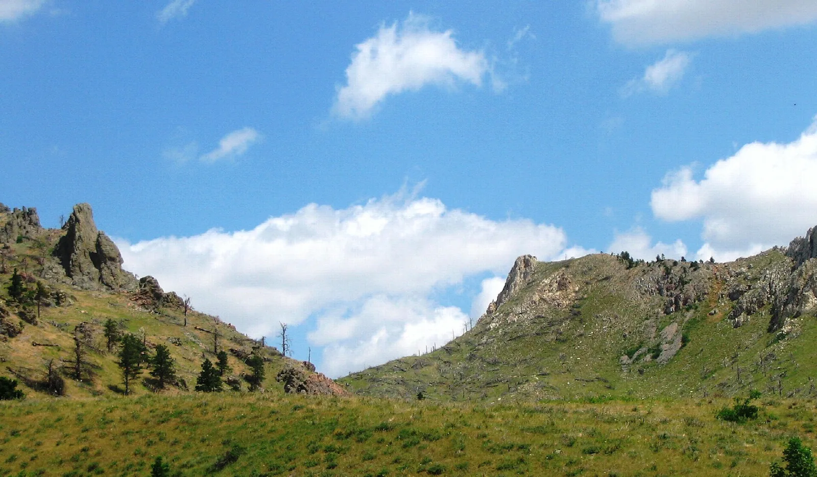 Grassy ridge with rocky outcrops under blue sky and clouds
