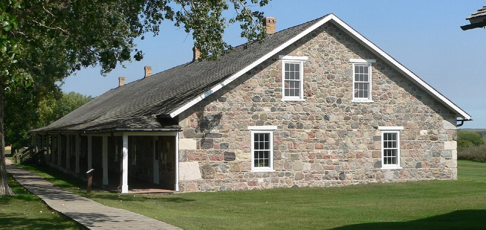 Long stone barracks building with a pitched roof and covered porch