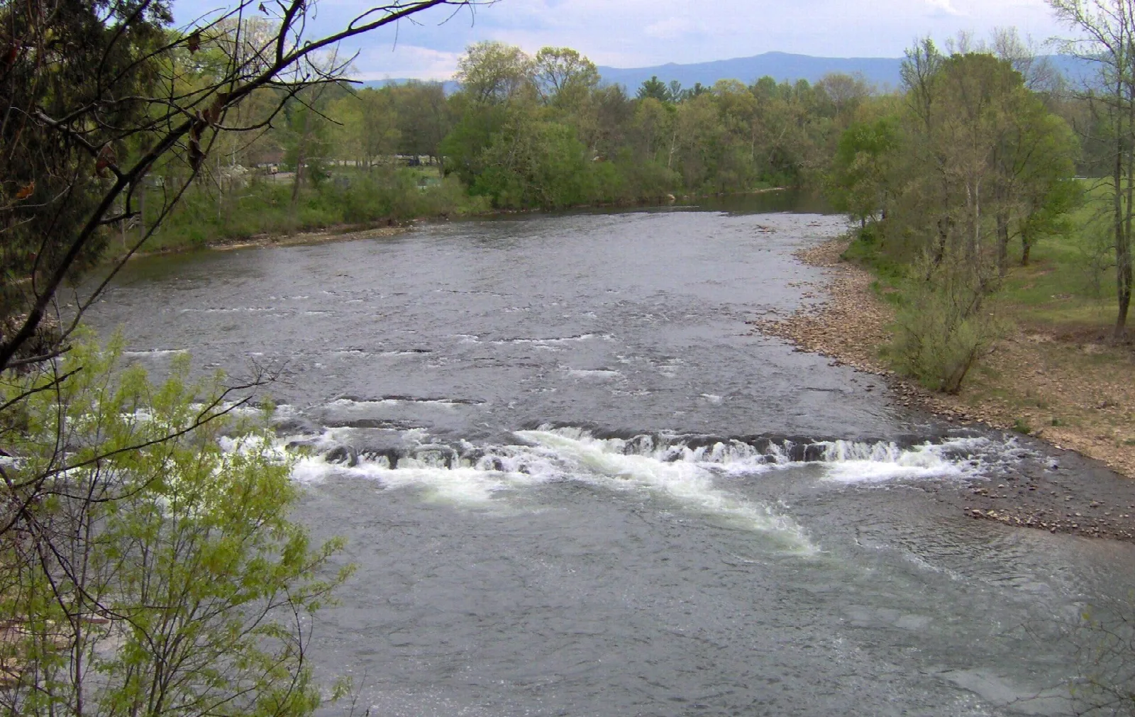 River flowing over a low ledge with green banks
