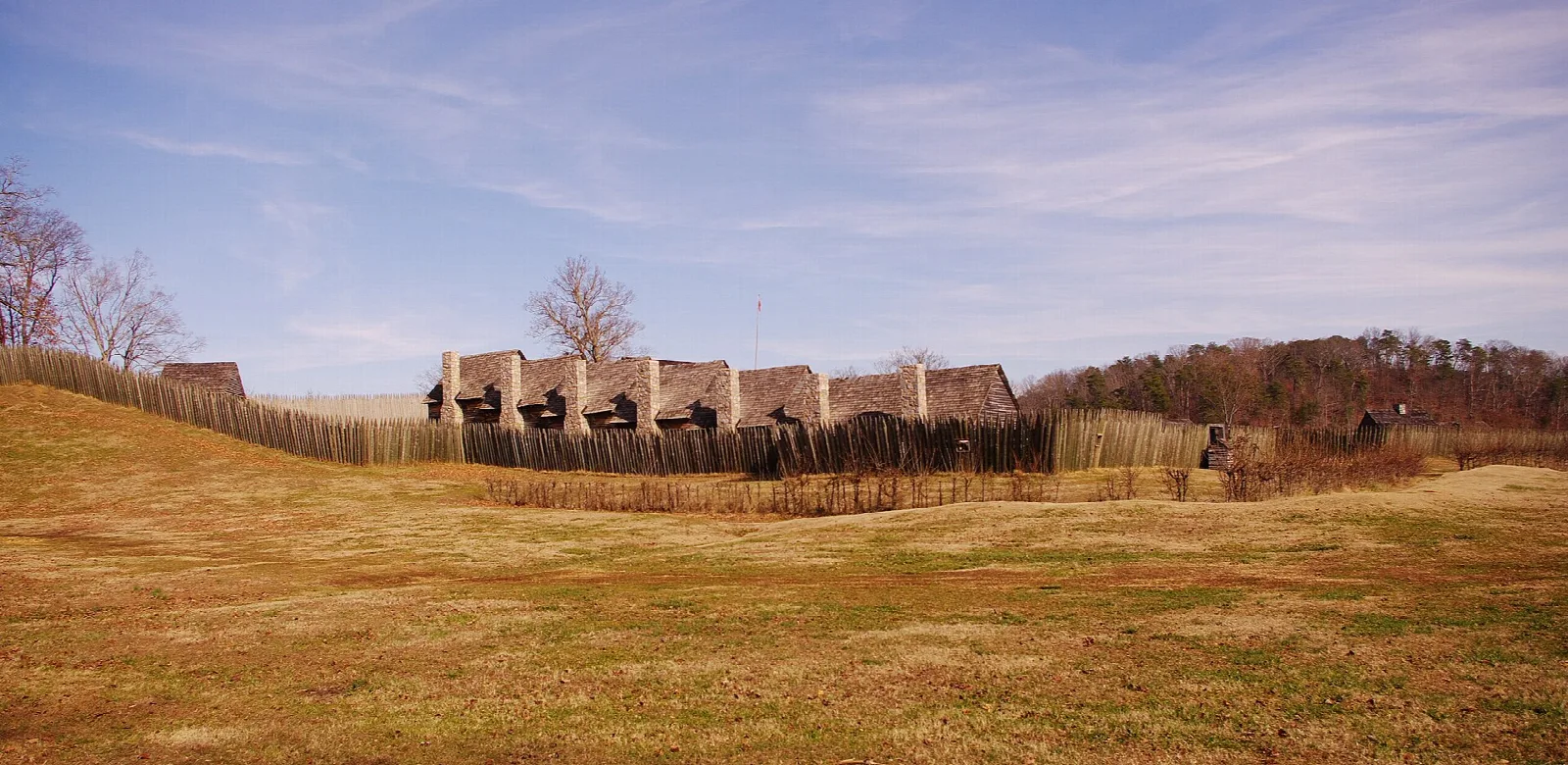 Reconstructed log fort across a grassy field under a purple sky