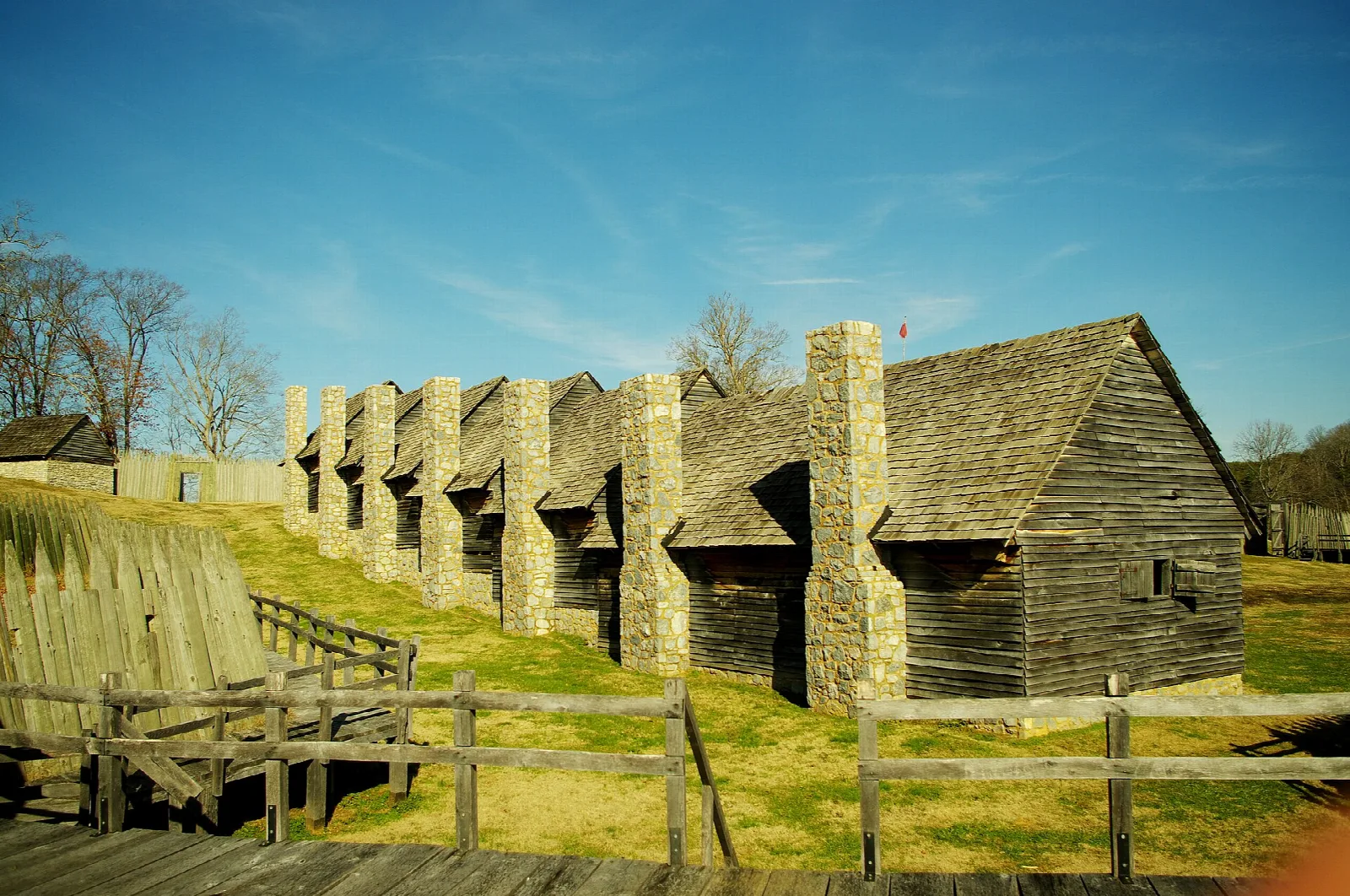 Wooden barracks buildings with stone chimneys inside a log palisade