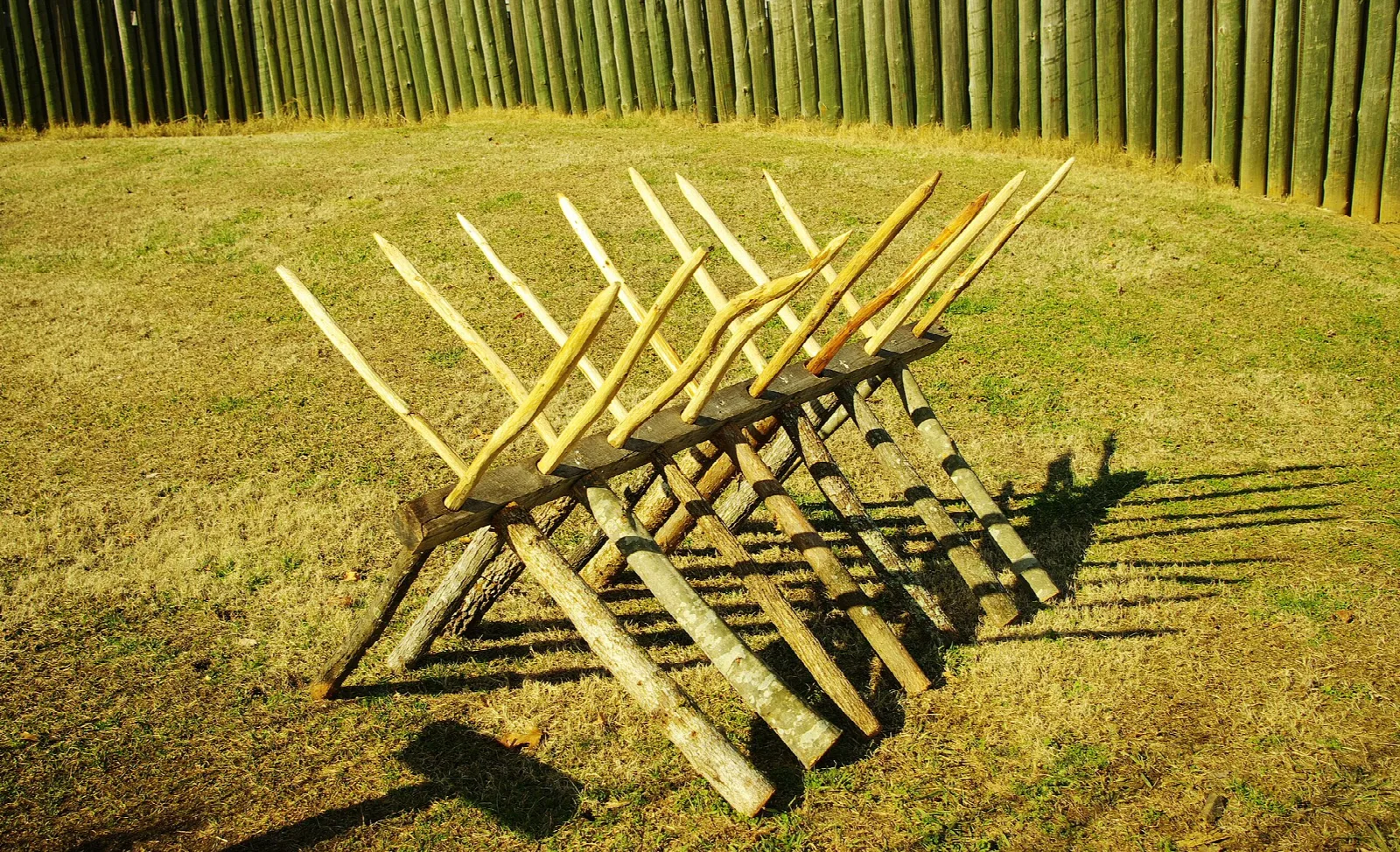 Wooden spiked barrier on grass in front of the fort wall