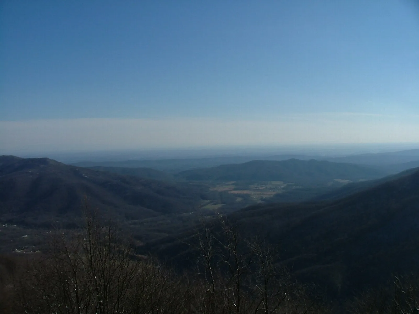 Dark forested ridges and valley under a clear blue sky