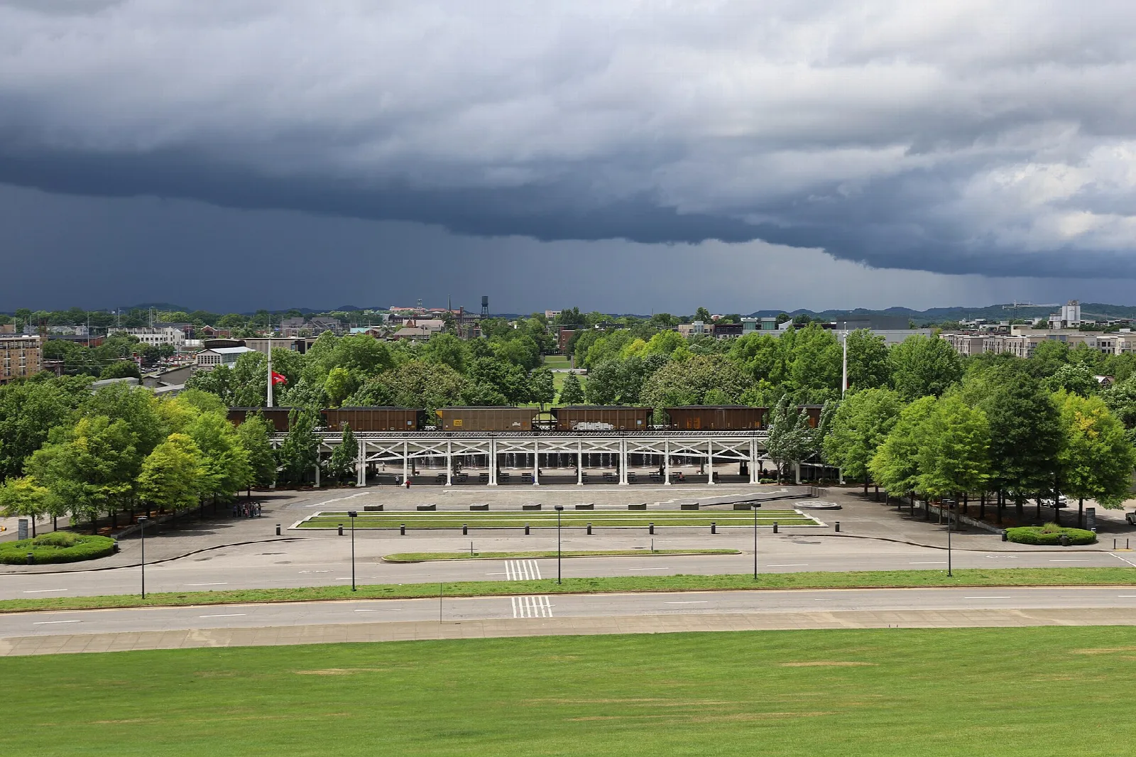 Park lawn and trees under a dark storm cloud
