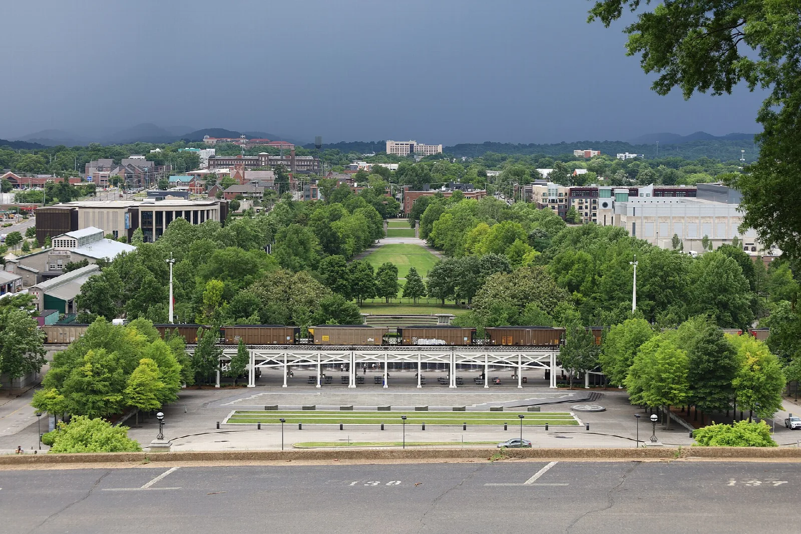 Tree-filled city park with a long pavilion seen from above