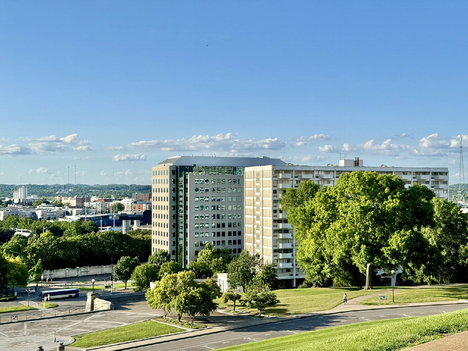 Green lawn slope with city buildings beyond under a blue sky