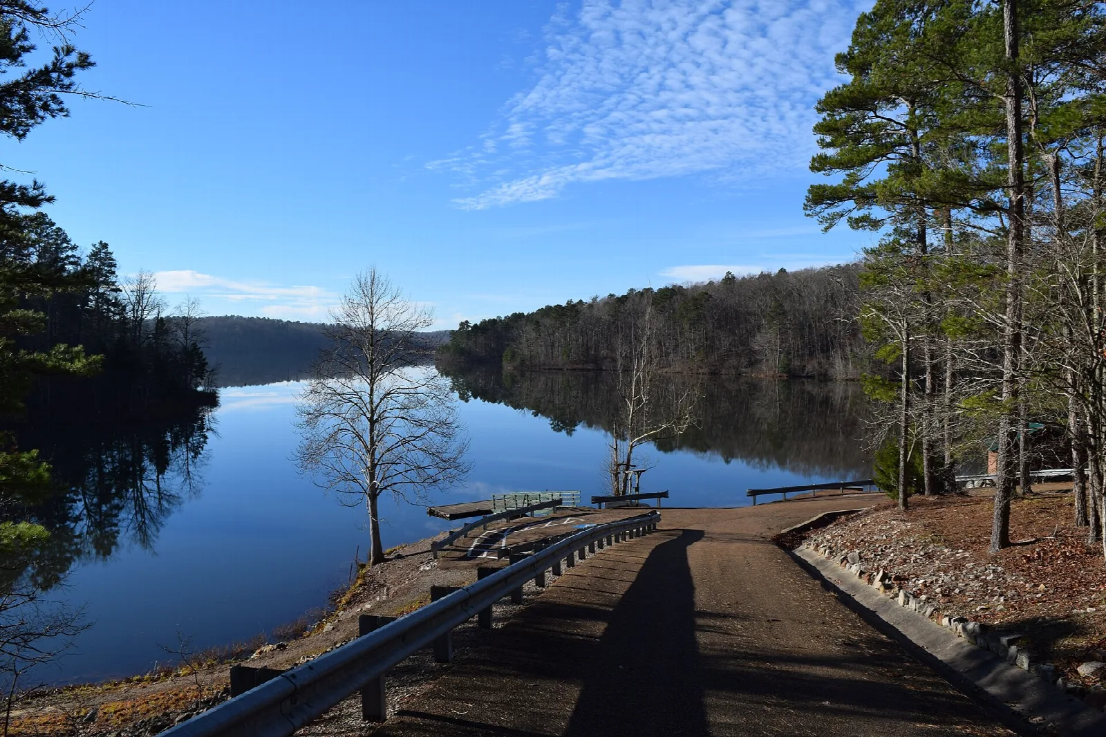 Boat ramp leading to a still lake with trees along the shore
