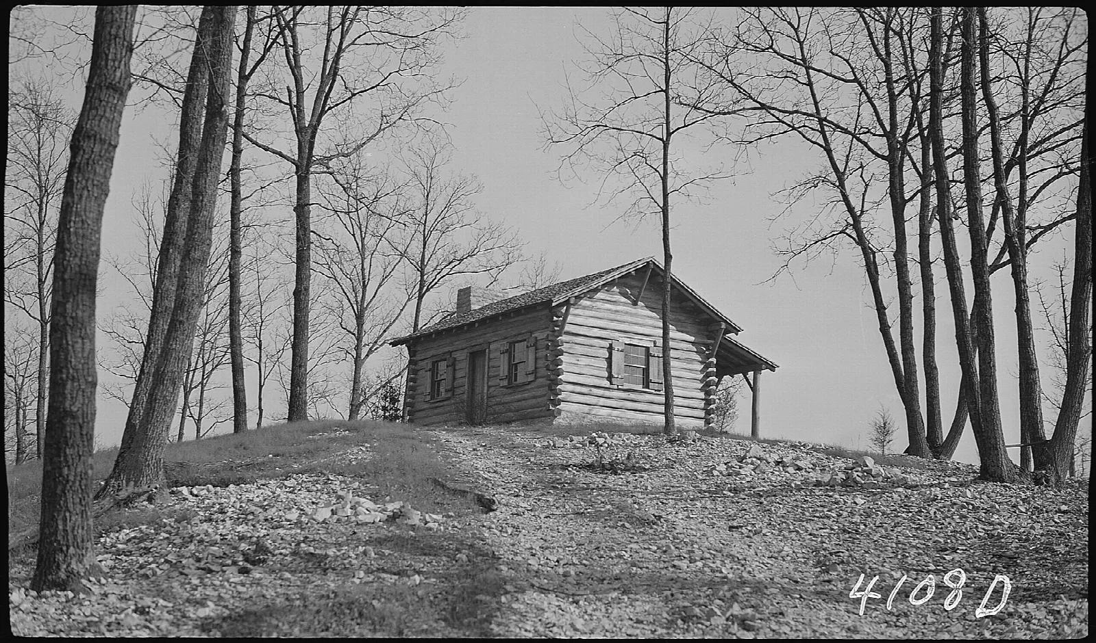 Historic black and white photo of a log cabin on a hill