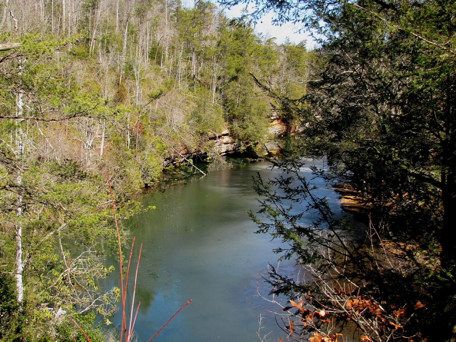Still green water lined by forested bluffs