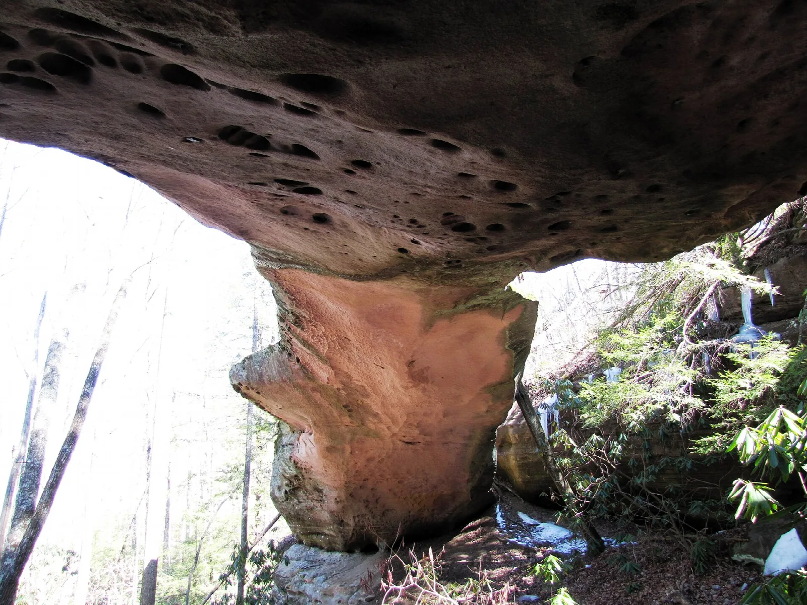 Natural stone arch seen from beneath with daylight beyond