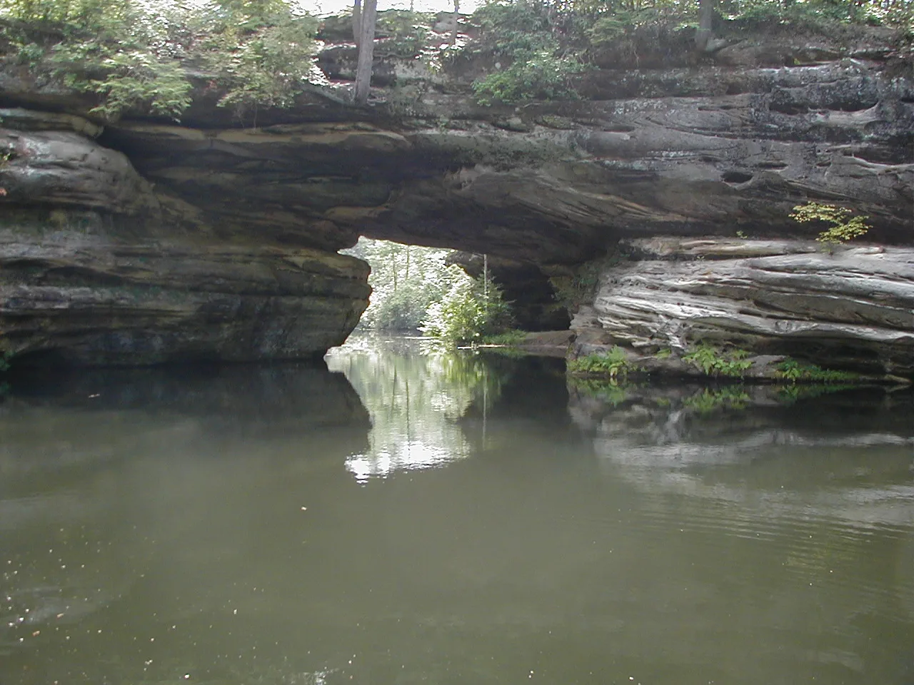 Still water beneath a rock overhang and arch
