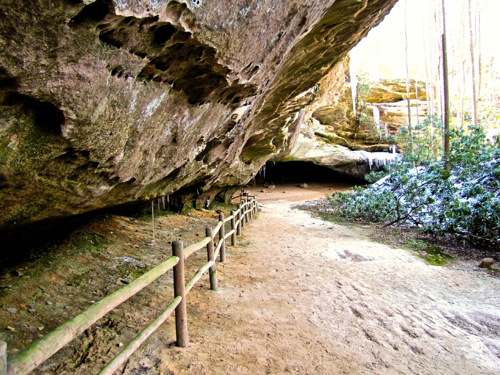 Gravel path along a rock overhang with a wooden fence