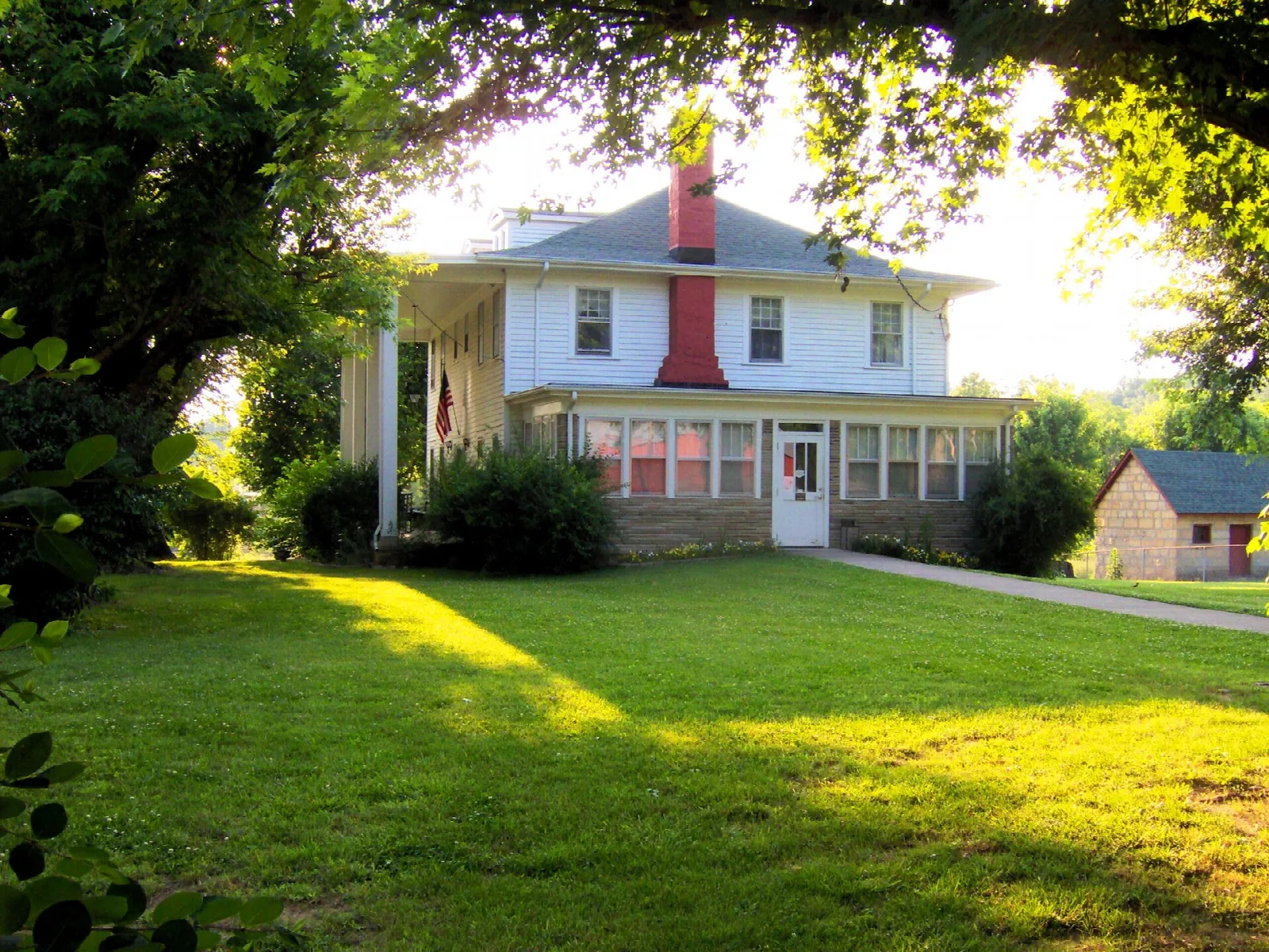 White house with a red chimney on a sunlit green lawn