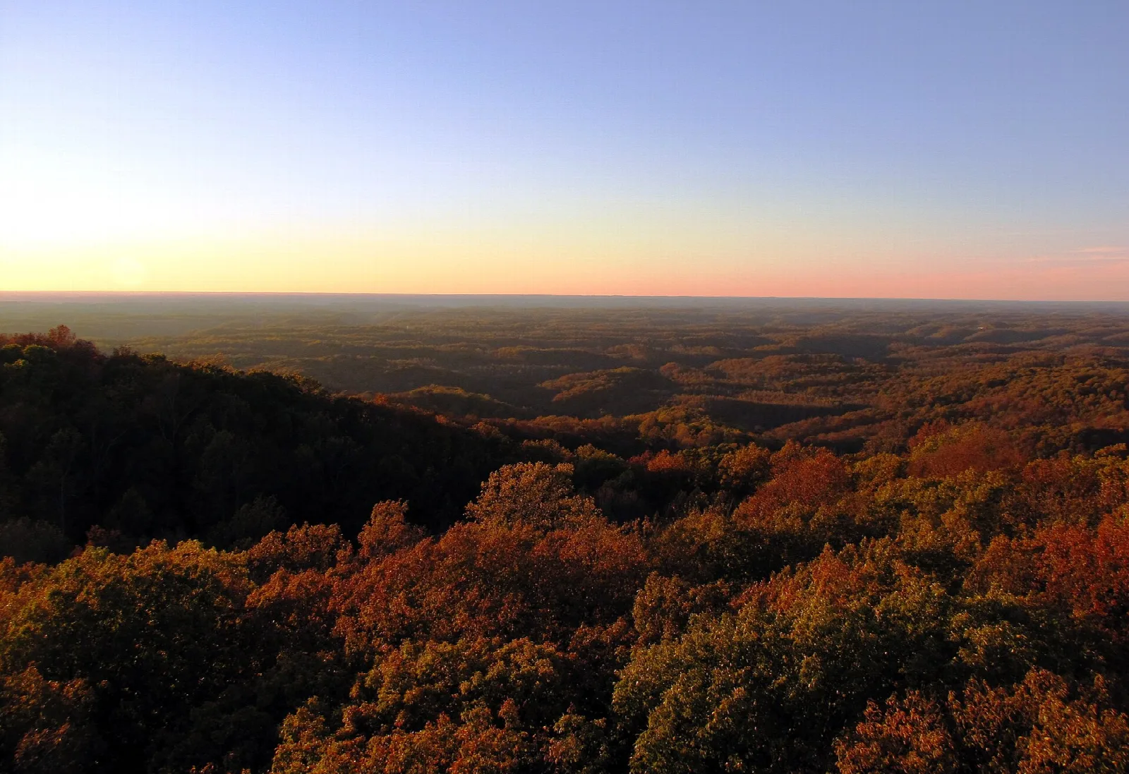 Sunset glow over forested hills seen from a fire tower