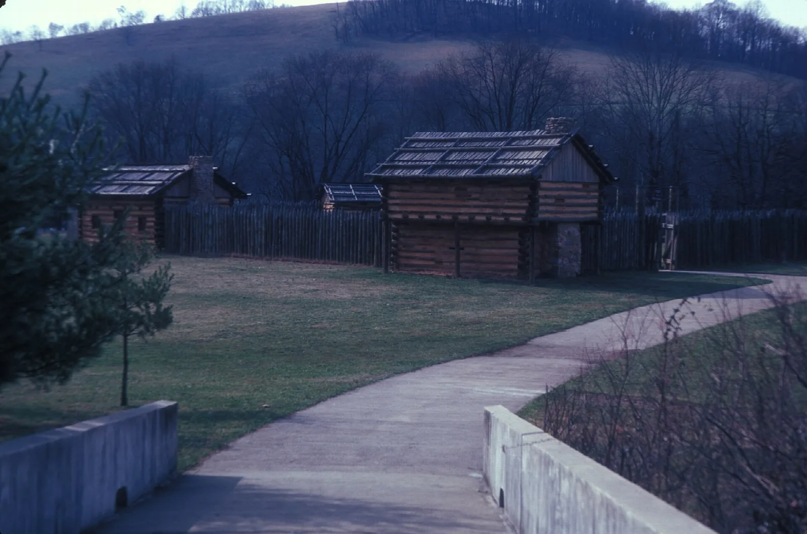 Log buildings inside a fort wall beside a curved walkway