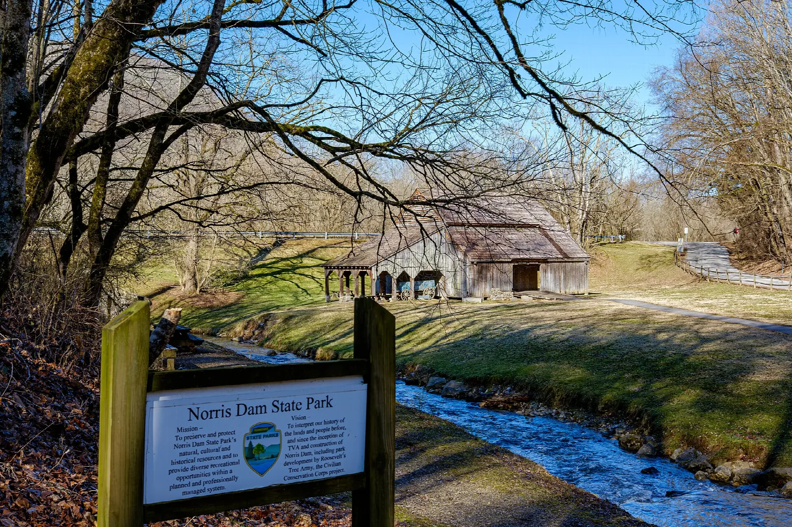 Old barn above a small stream behind a park sign