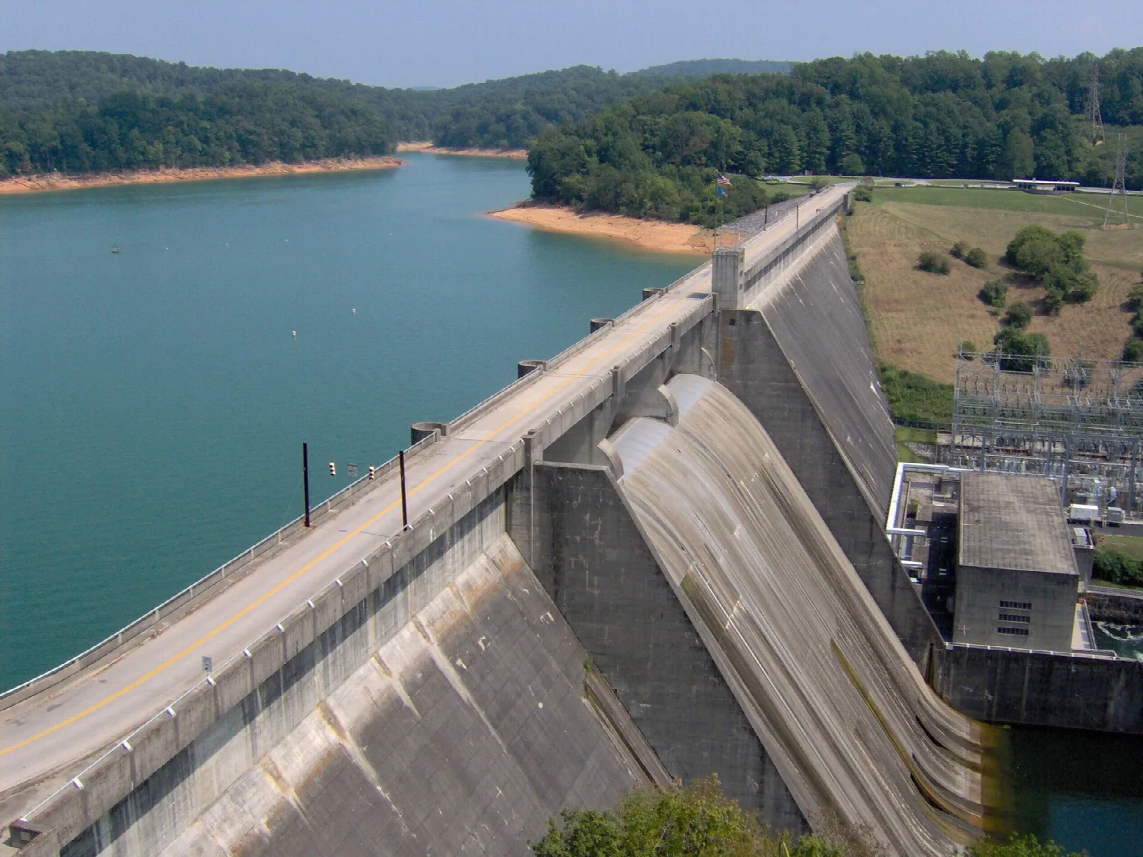 Large concrete dam holding back a blue-green lake