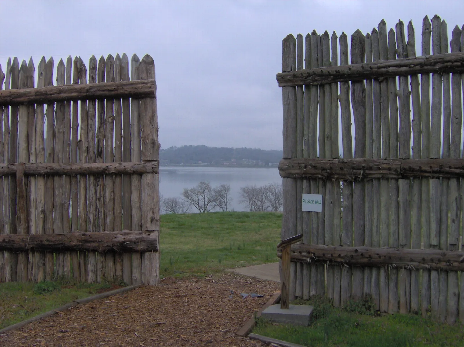 Tall wooden palisade posts with a river in the distance
