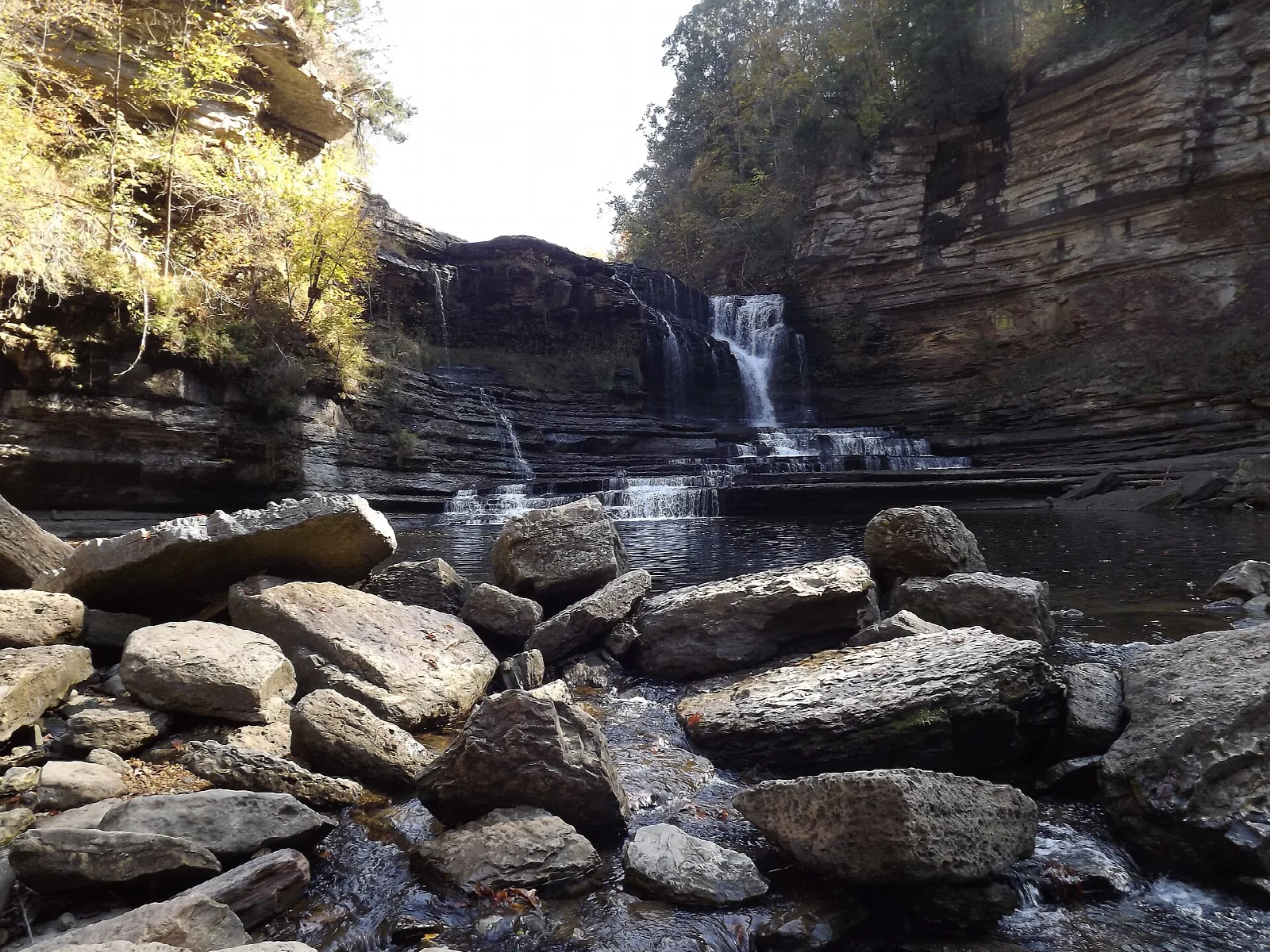 Boulders in the foreground with a waterfall in a rocky gorge behind