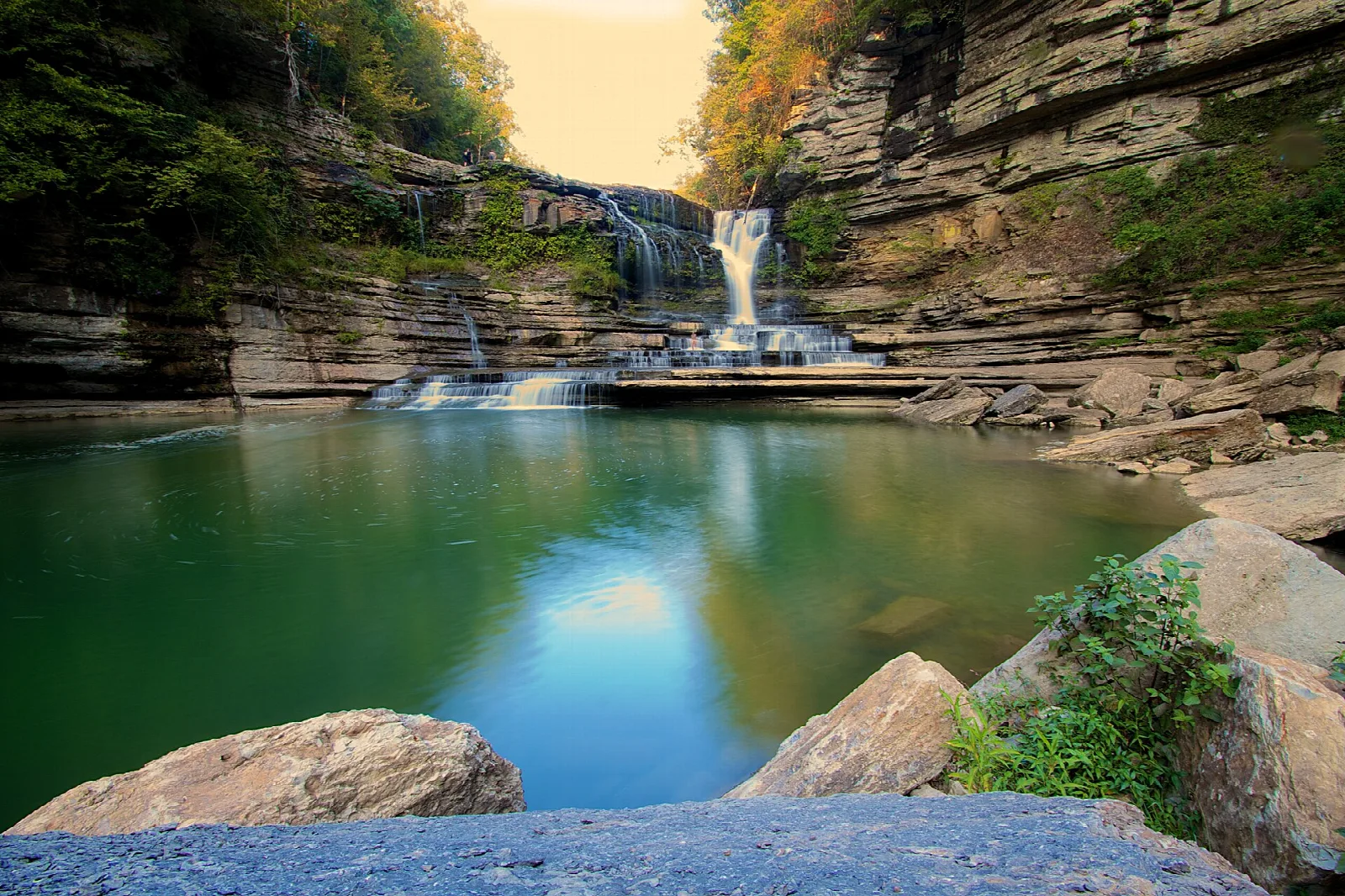 Green plunge pool below a waterfall in a rock gorge