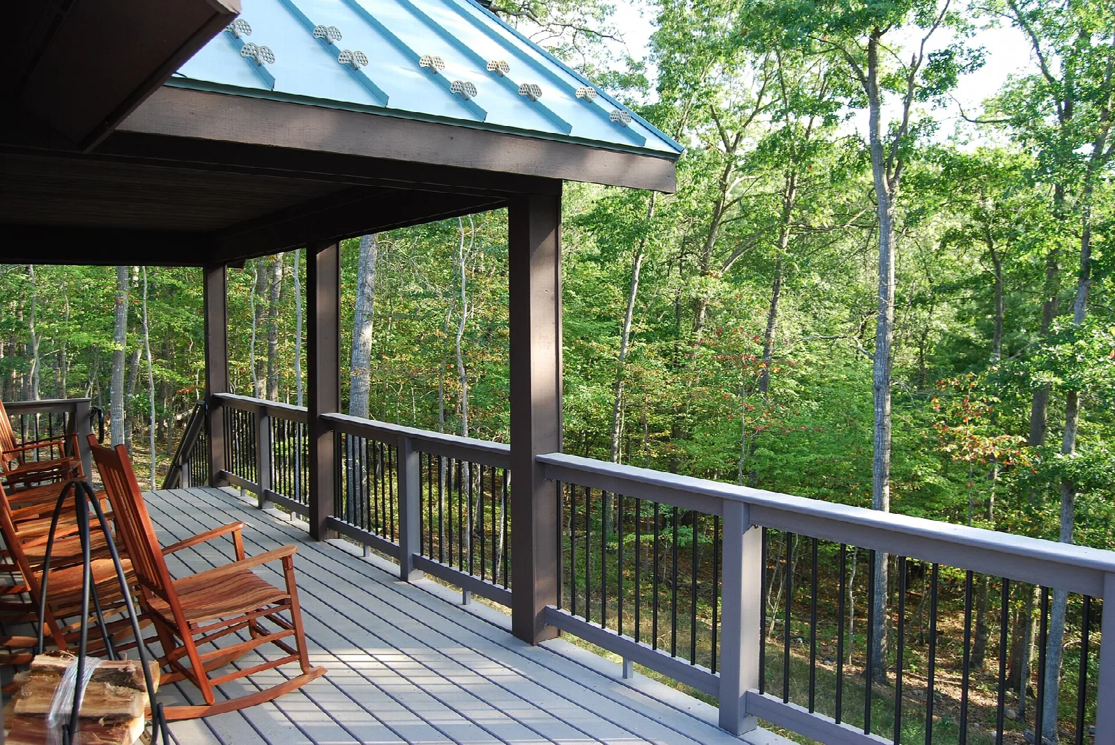 Covered cabin porch with rocking chairs looking out over green forest