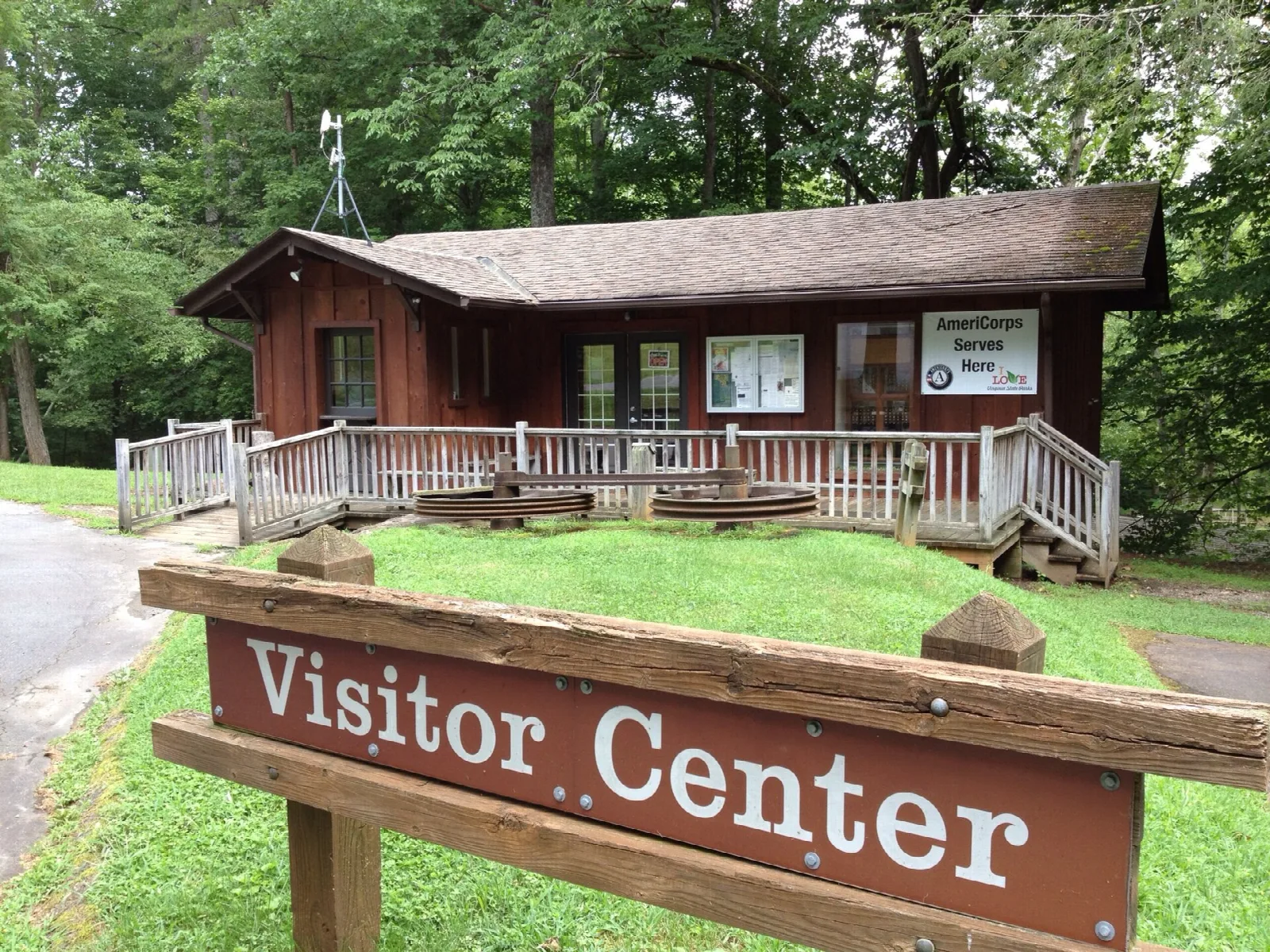Brown visitor center building with porch and a wooden Visitor Center sign