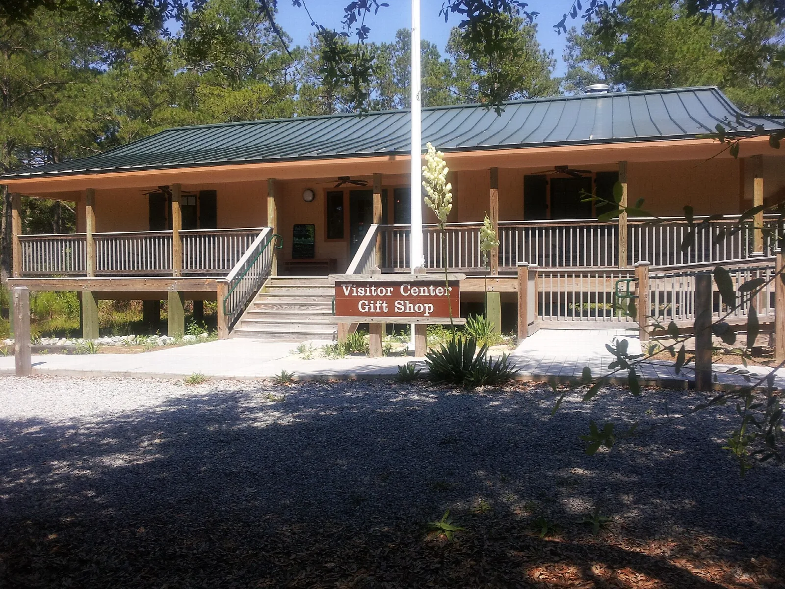 Wooden visitor center with a porch, flagpole and Gift Shop sign