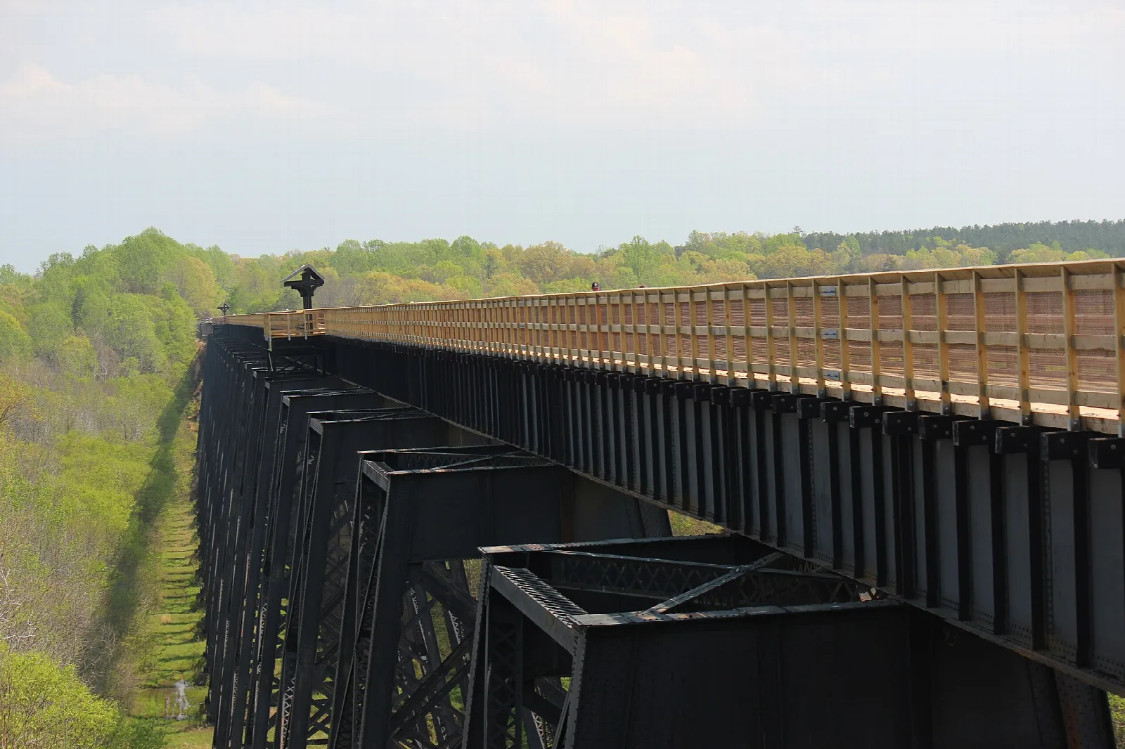 Long wooden-decked trestle bridge stretching above a forested valley