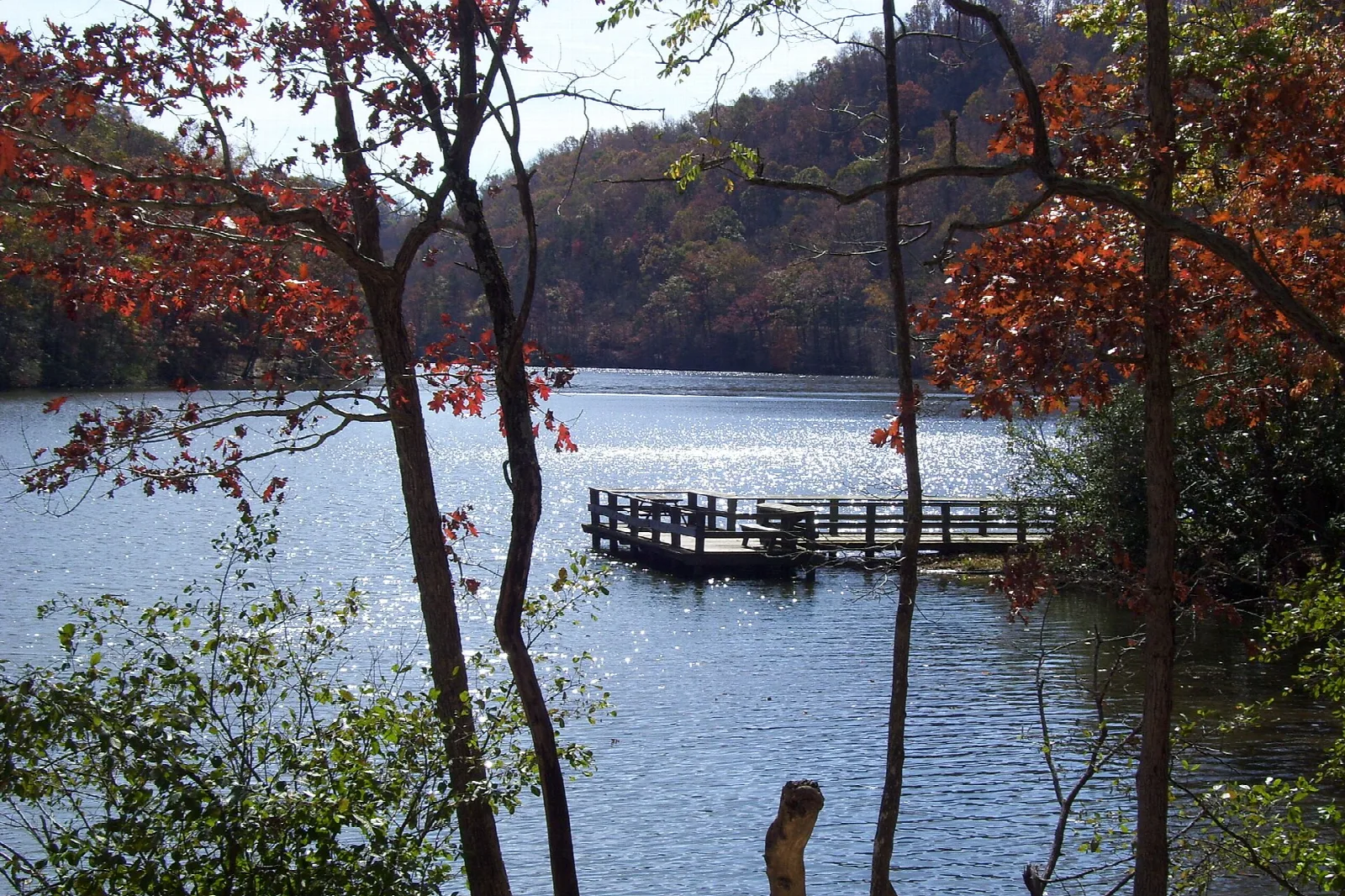 Fishing pier on a mountain lake ringed by red autumn trees