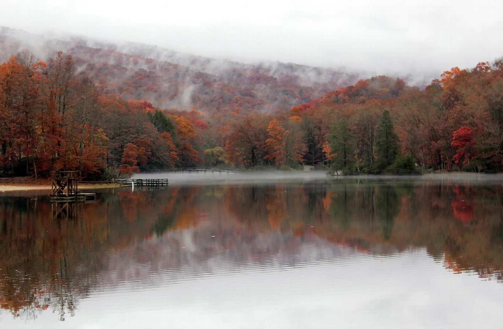 Misty autumn hills reflected in a still lake