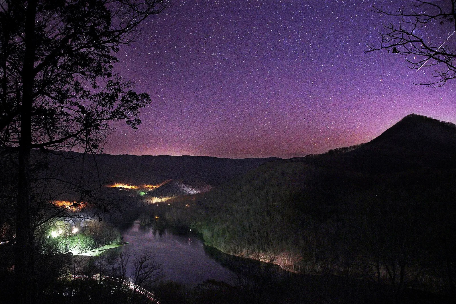 Night sky with stars over a lake valley and a mountain ridge