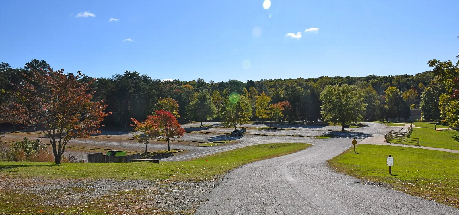 Gravel road through an open park area with fall trees