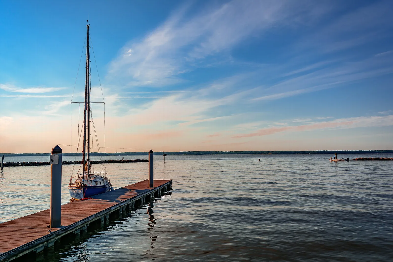 Sailboat tied at a dock on the river under a blue sky