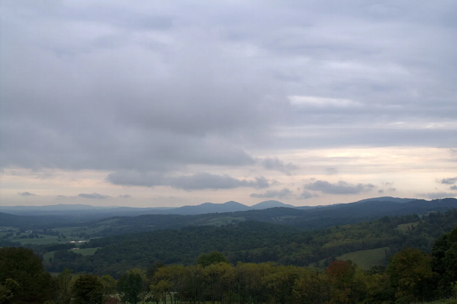 Cloudy sky over layered mountain ridges and wooded valleys