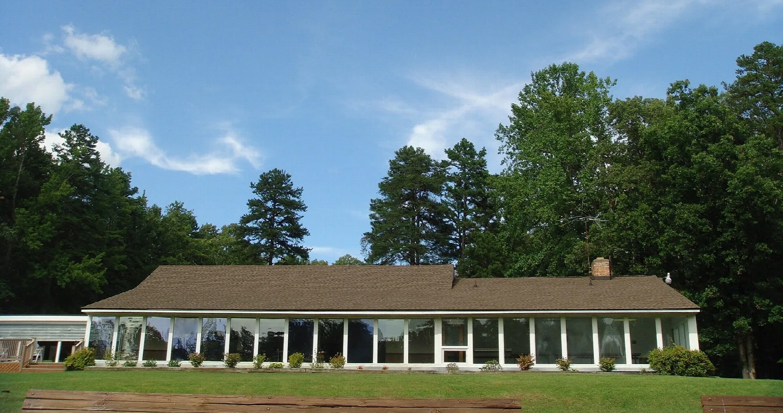 Long low lodge with a porch and lawn in front of tall pines