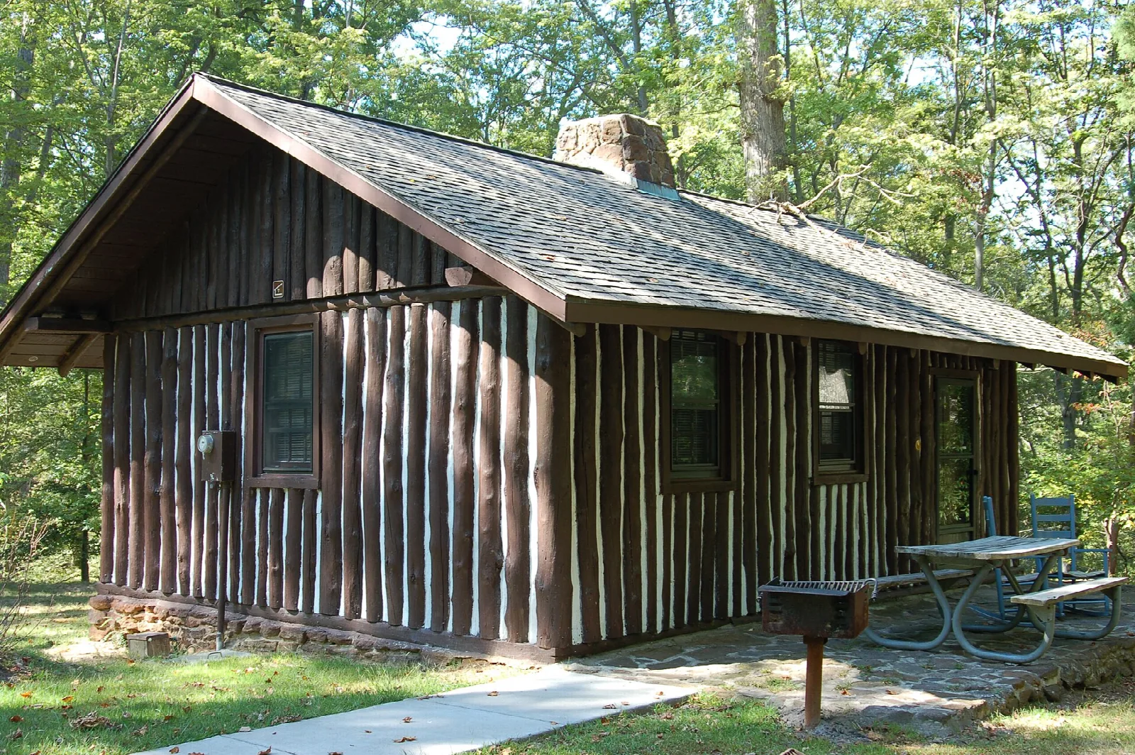 Rustic log cabin with a porch and picnic table in the woods