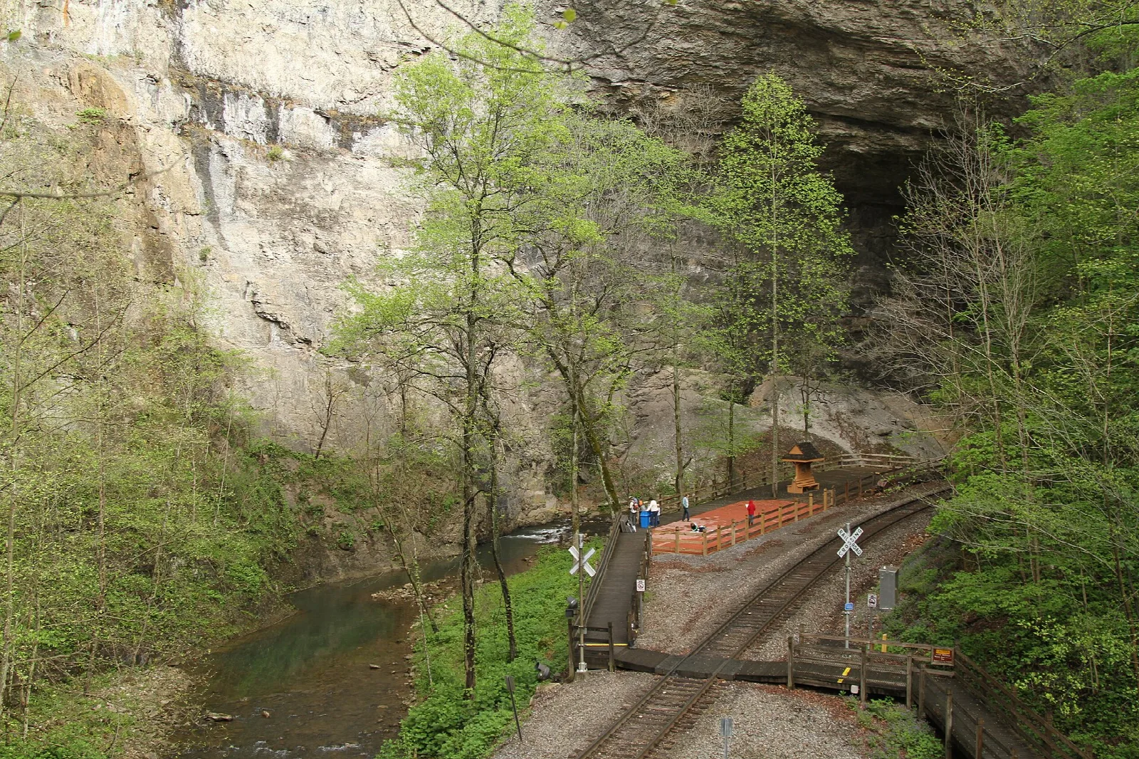 Railroad track and boardwalk beneath a tall rock wall