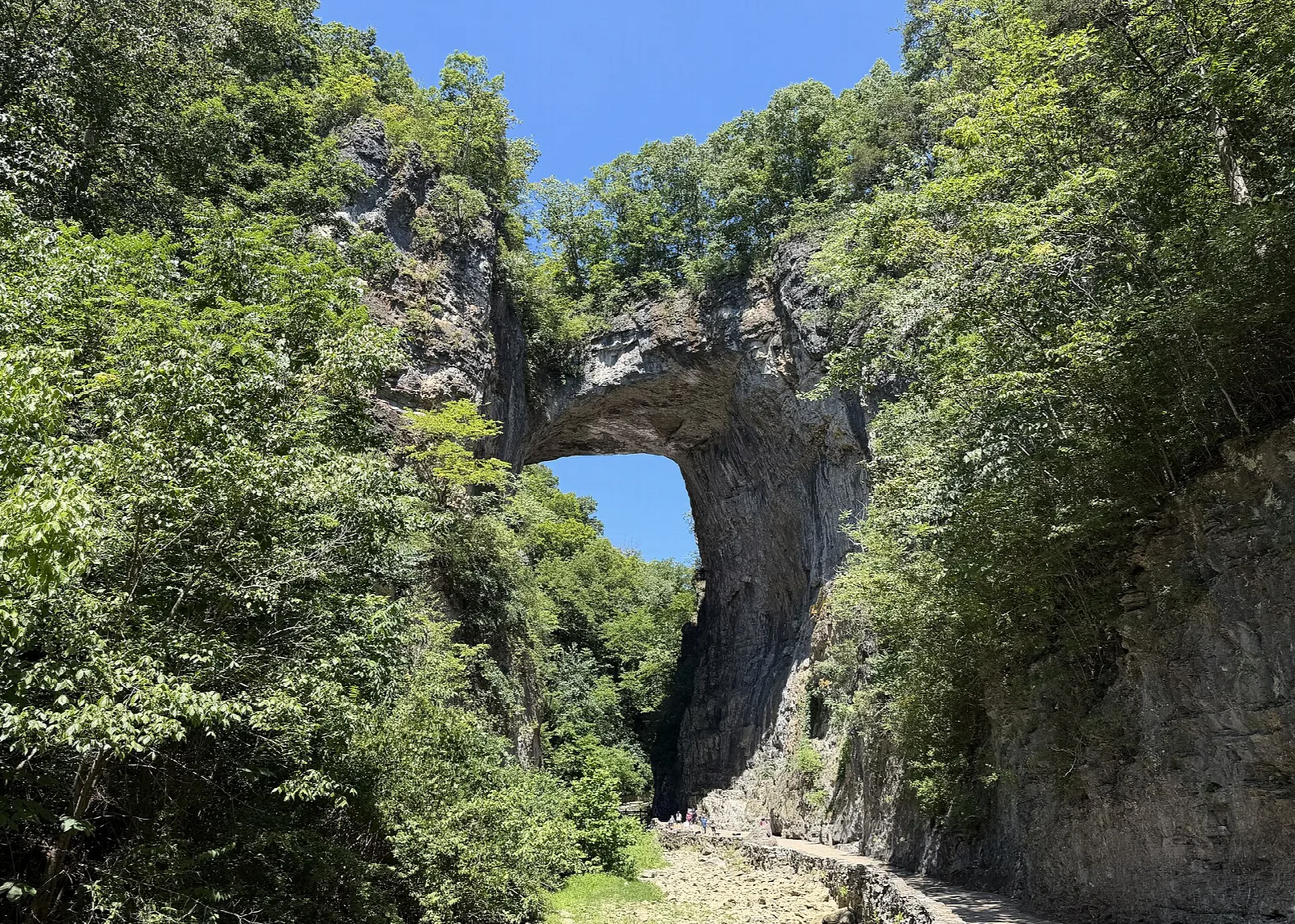 Stone arch spanning a gorge, framed by green trees